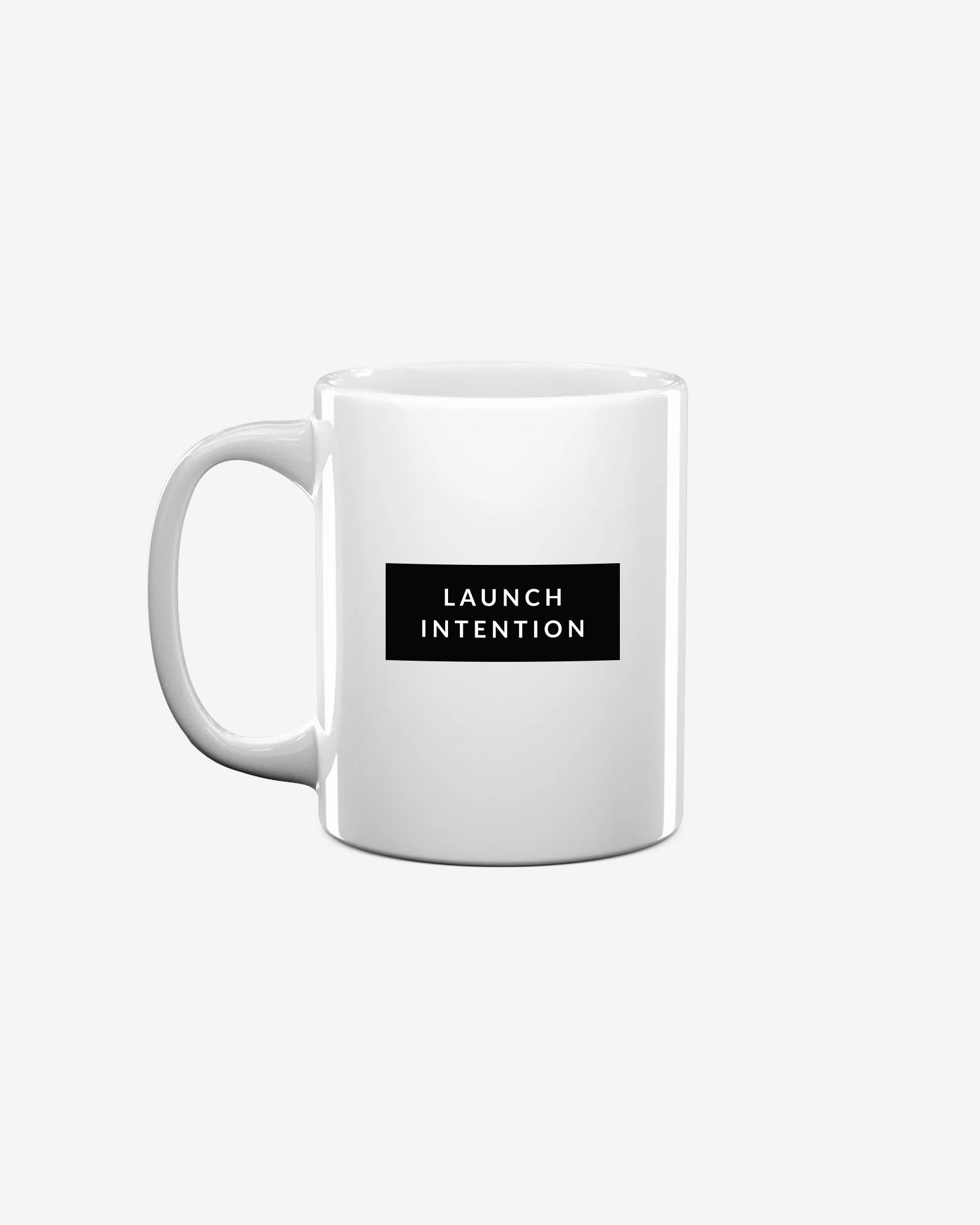 Left side of white Launch Intention staple coffee mug with paper plane branding