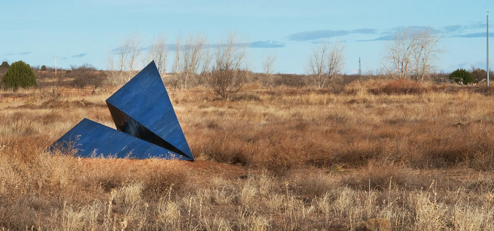 Large Launch Intention metallic paper airplane sculpture in a field at the Art City outdoor museum in New Mexico.