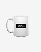 Left side of white Launch Intention staple coffee mug with paper plane branding