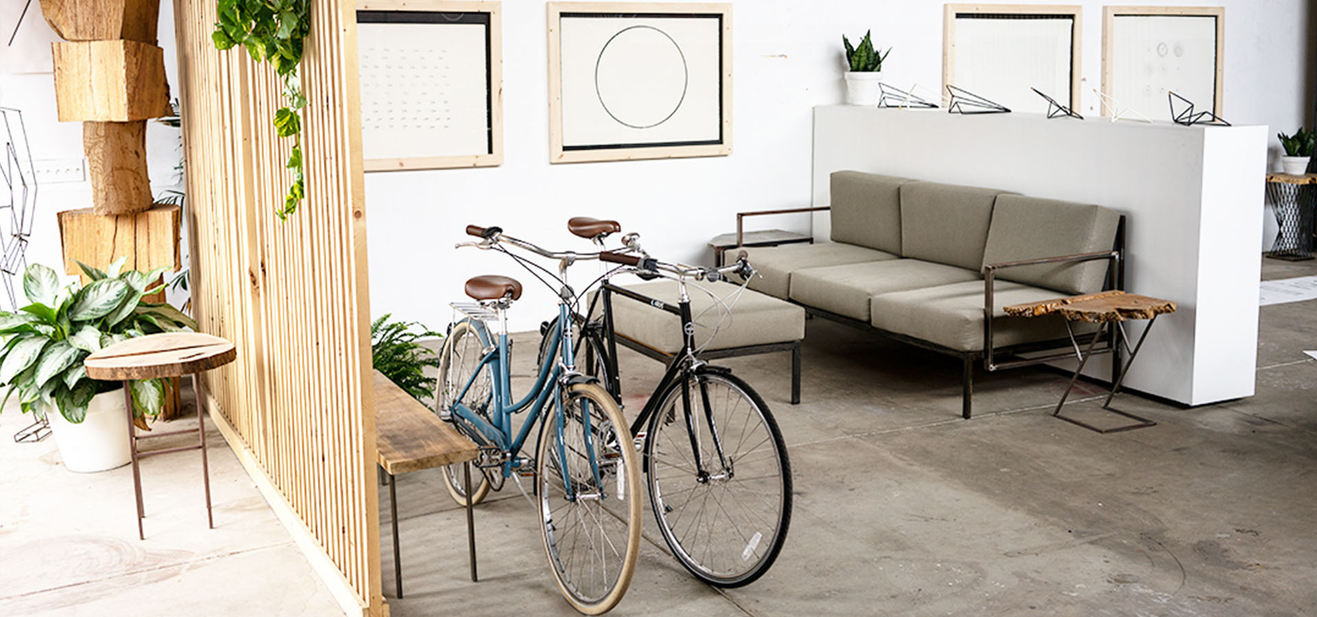 Gallery wall and lounge with bikes and a wooden slat wall frame Launch Intention small sculptures on a shelf at a Venice International Airport Studio activation.