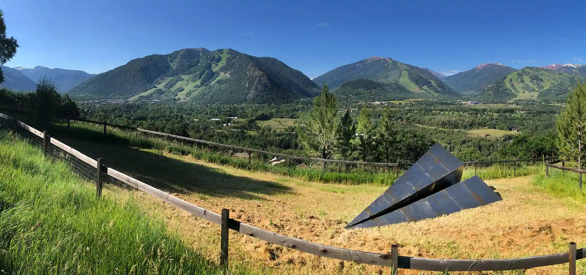 Launch Intention Paper Airplane Sculpture rests in a grassy field with the Aspen mountains in the background.