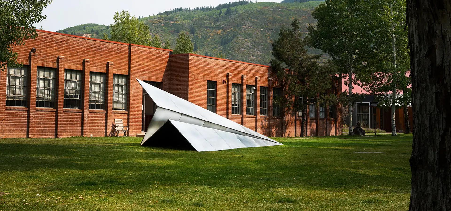 Large Launch Intention metallic paper airplane sculpture in front of the Red Brick School in Aspen, Colorado for Aspen Art Week.