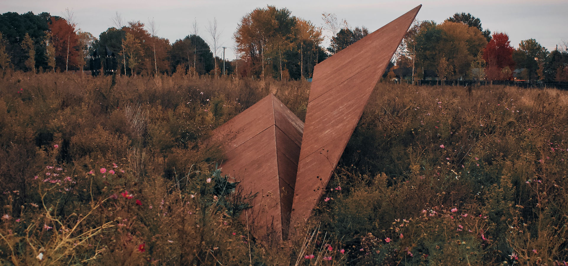  Rust-toned Launch Intention paper airplane sculpture by Griffin Loop at Osage Park surrounded by fall foliage, large-scale contemporary public art inviting reflection and shared intention 