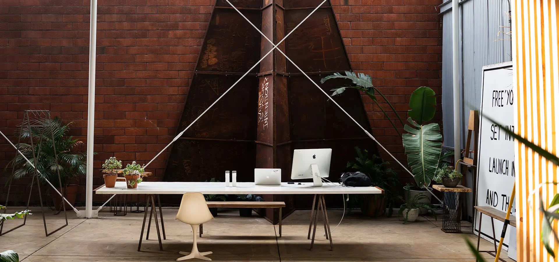 Modern office setup with a desk, chairs, and decor in a stylish interior with a large Launch Intention metal paper airplane sculpture in the background at the Venice International Airport Studio.