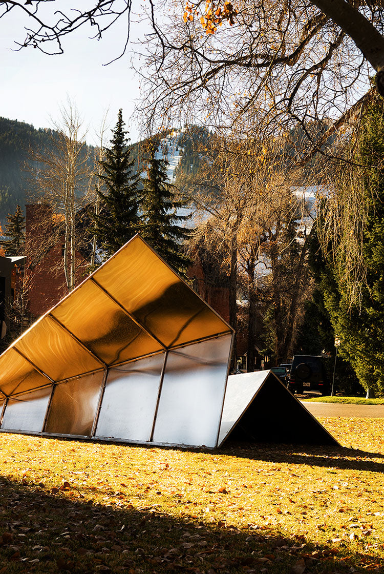 Modern Paper Airplane Sculpture by Launch Intention in Aspen Colorado's beautiful setting with trees and mountains.