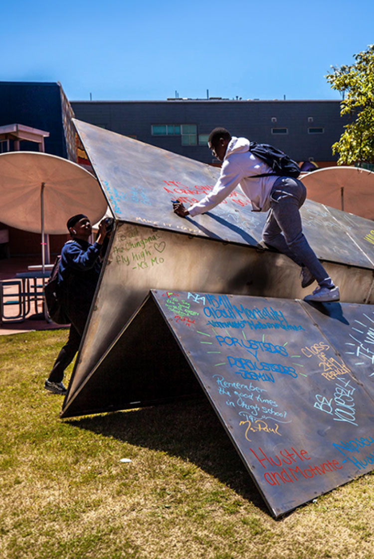 Students write intentions on the Launch Intention metal paper plane sculpture at the Maya Angelou Mural Festival Installation in Los Angeles.