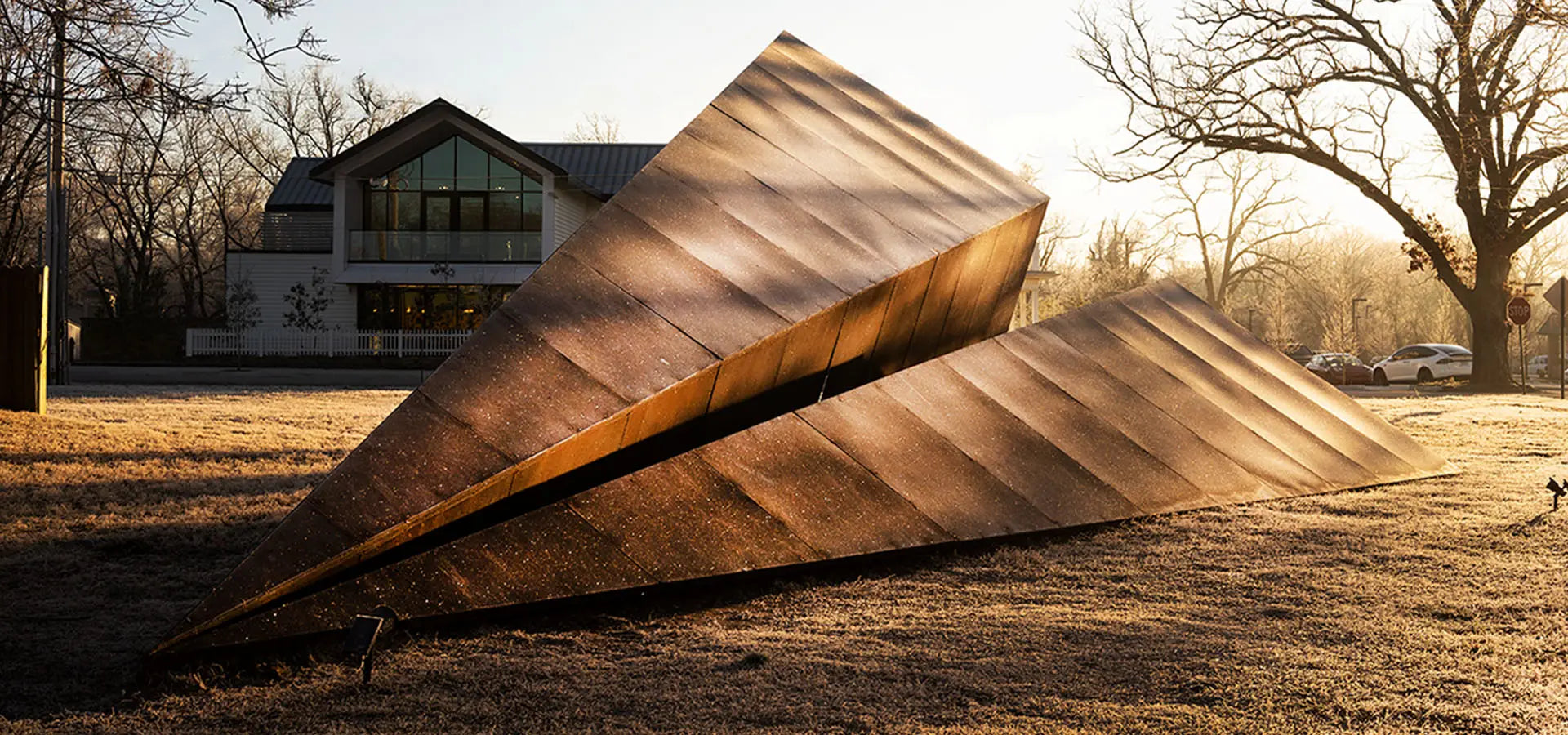 Launch Intention's large 50 foot metal paper airplane sculpture in a Bentonville Arkansas park in front of the Blake Street building.