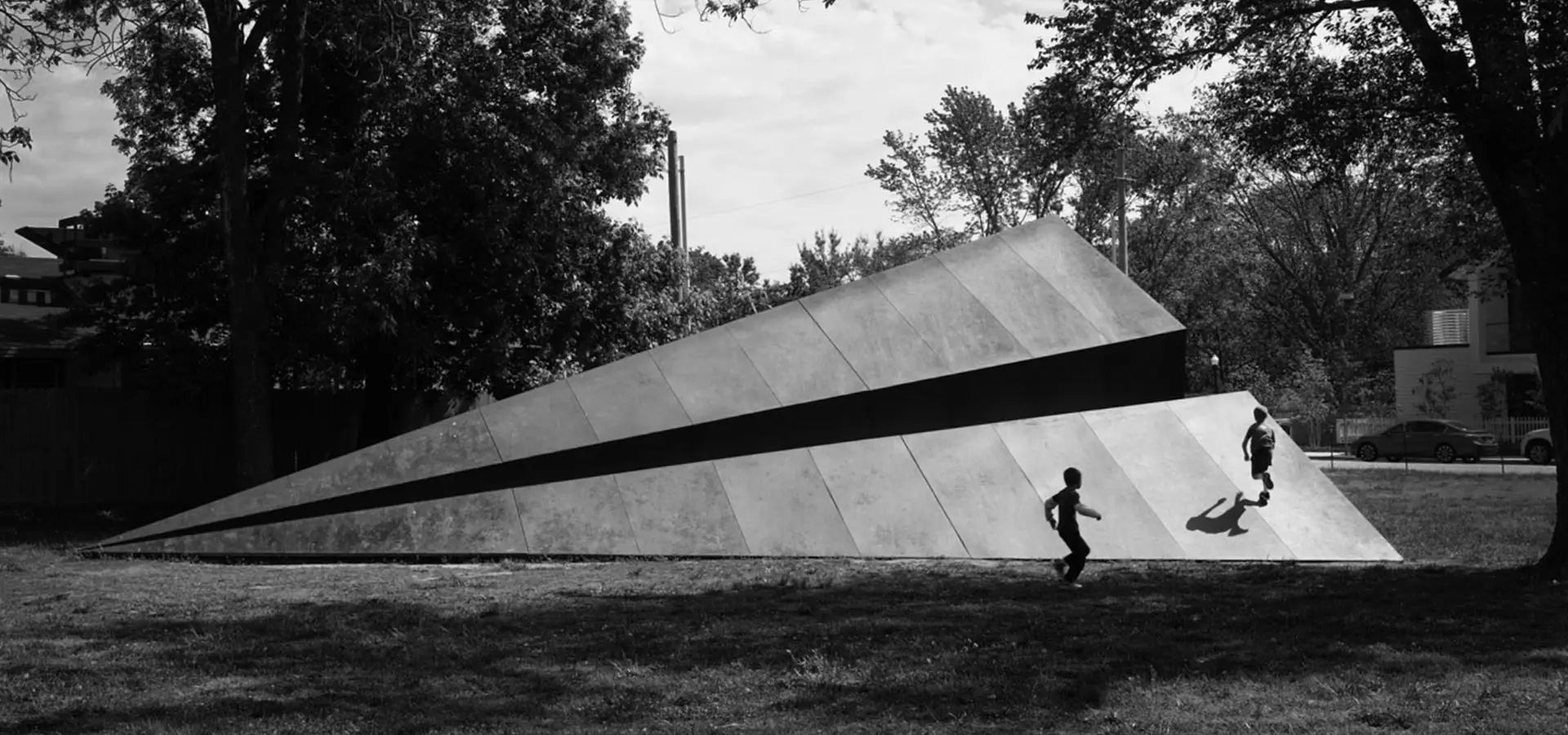 Children playing on the 50ft Launch Intention Paper Airplane Sculpture in Bentonville, Arkansas downtown in black and white.