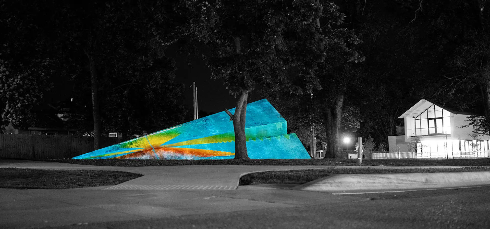 Launch Intention's large 50 foot metal paper airplane sculpture in a Bentonville Arkansas park in front of the Blake Street building at night during a projection mapping activation.