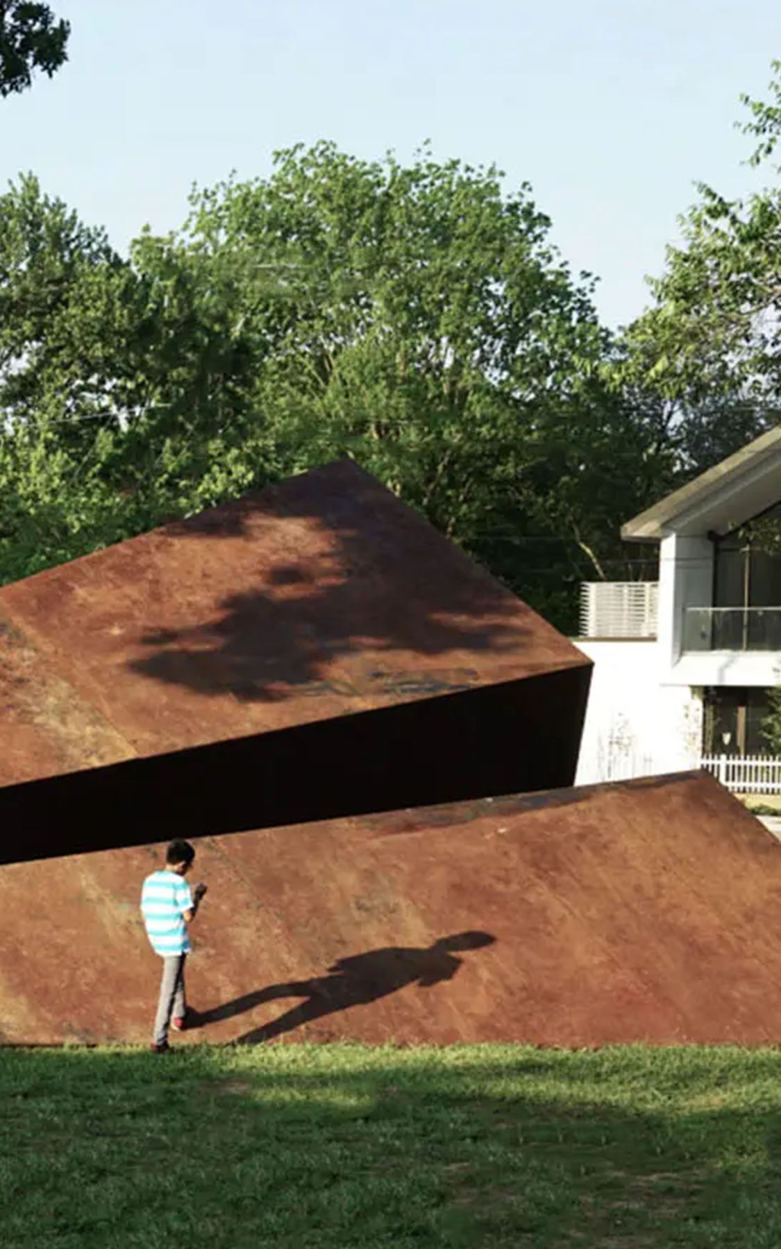 Large 50 foot metal paper airplane sculpture in a Bentonville Arkansas park with a person for scale by Launch Intention.
