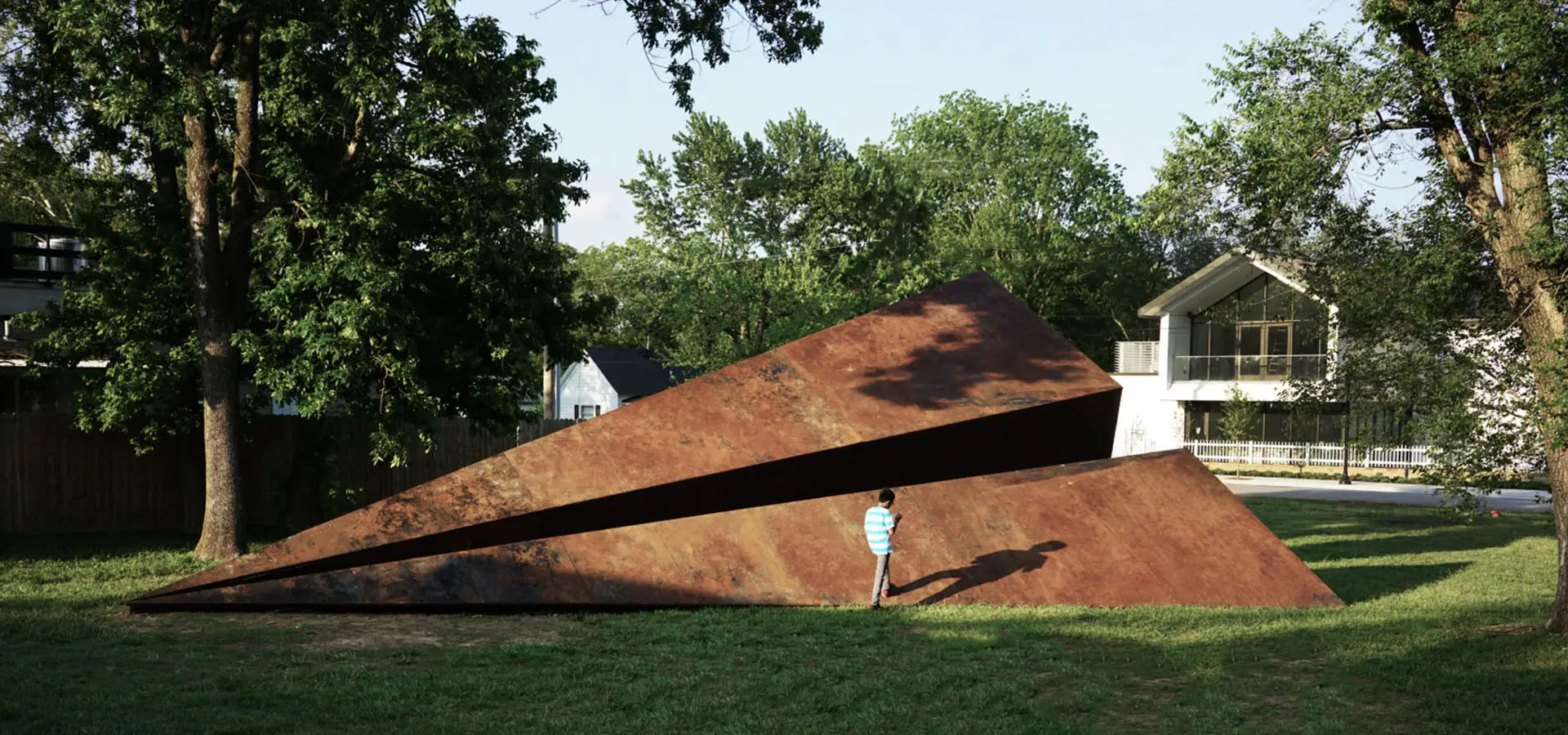 Large metal paper airplane sculpture in a Bentonville Arkansas park with a person for scale by Launch Intention.