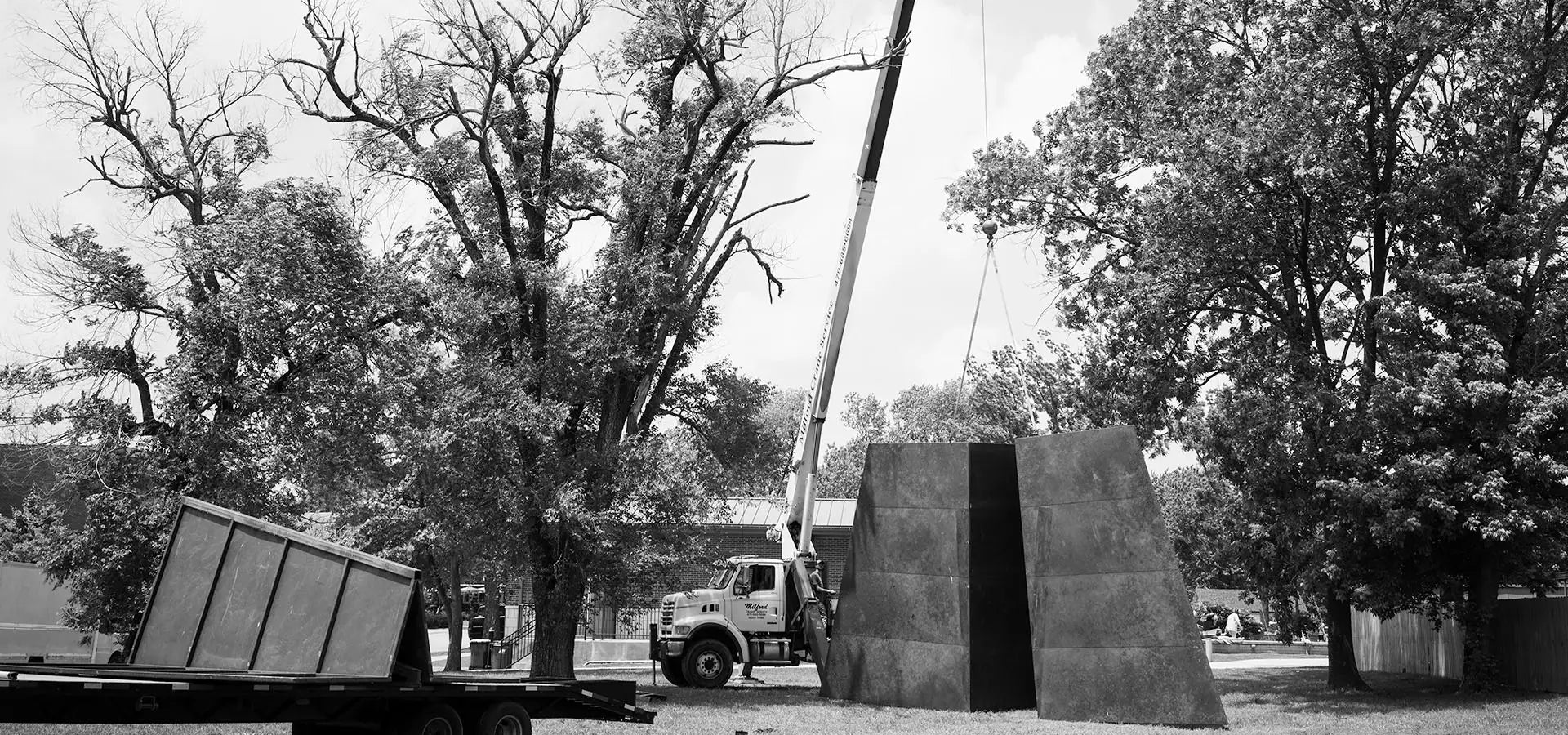 A large crane installs Launch Intention's large 50 foot metal paper airplane sculpture in a Bentonville Arkansas park in front of the Blake Street building.