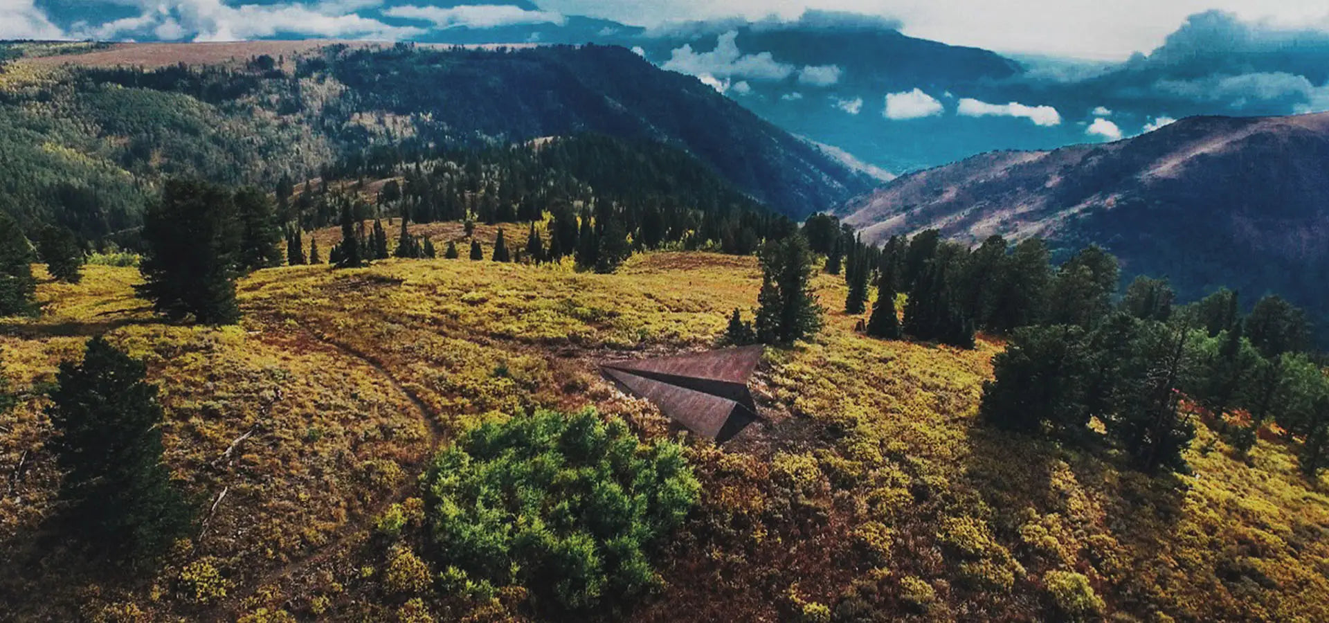 Launch Intention's 50Ft Paper Airplane Sculpture at Powder Mountain in a scenic view of the Eden Valley landscape with green trees and blue sky.