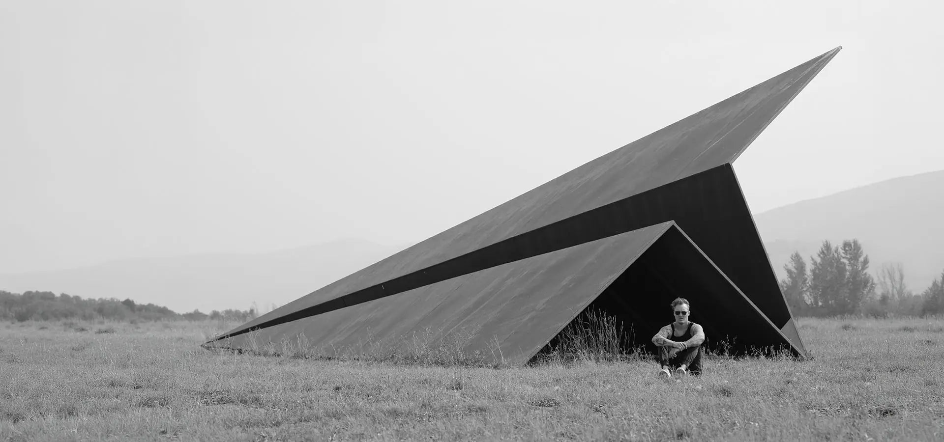 Artist and Founder Griffin Loop sits in front of the original Launch Intention installation at the 50ft Paper Airplane sculpture at Powder Mountain Utah.