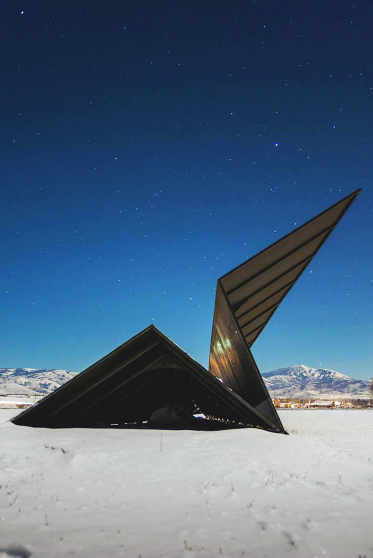 Modern architectural paper airplane sculpture by Launch Intention in a snowy landscape with Utah mountains in the background.