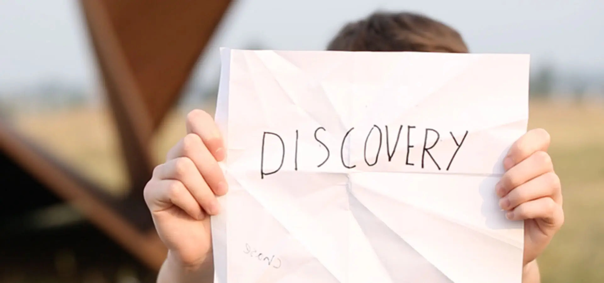 The Original Launch Intention 50 Foot Paper Airplane Sculpture activation shows a student holding his unfolded intention paper airplane with his intention "Discovery" written on it.