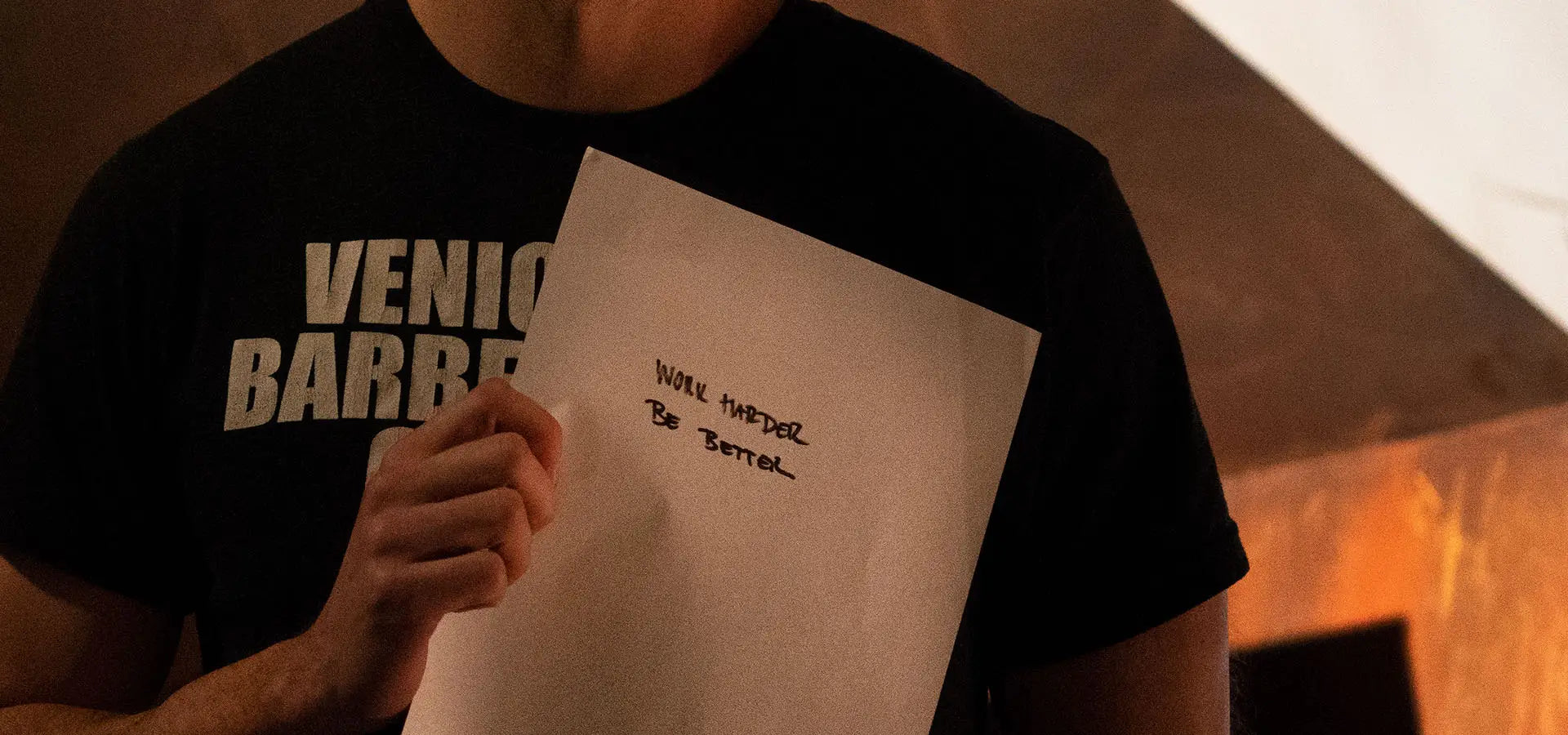 Man holding a Launch Intention paper with the intention "work harder be better" written on it at a Venice International Airport Studio activation.