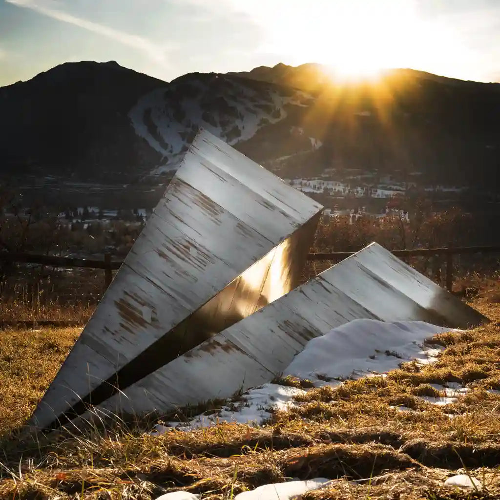 Metal Paper Airplane sculpture in a natural landscape with mountains and sun in Aspen, Colorado.