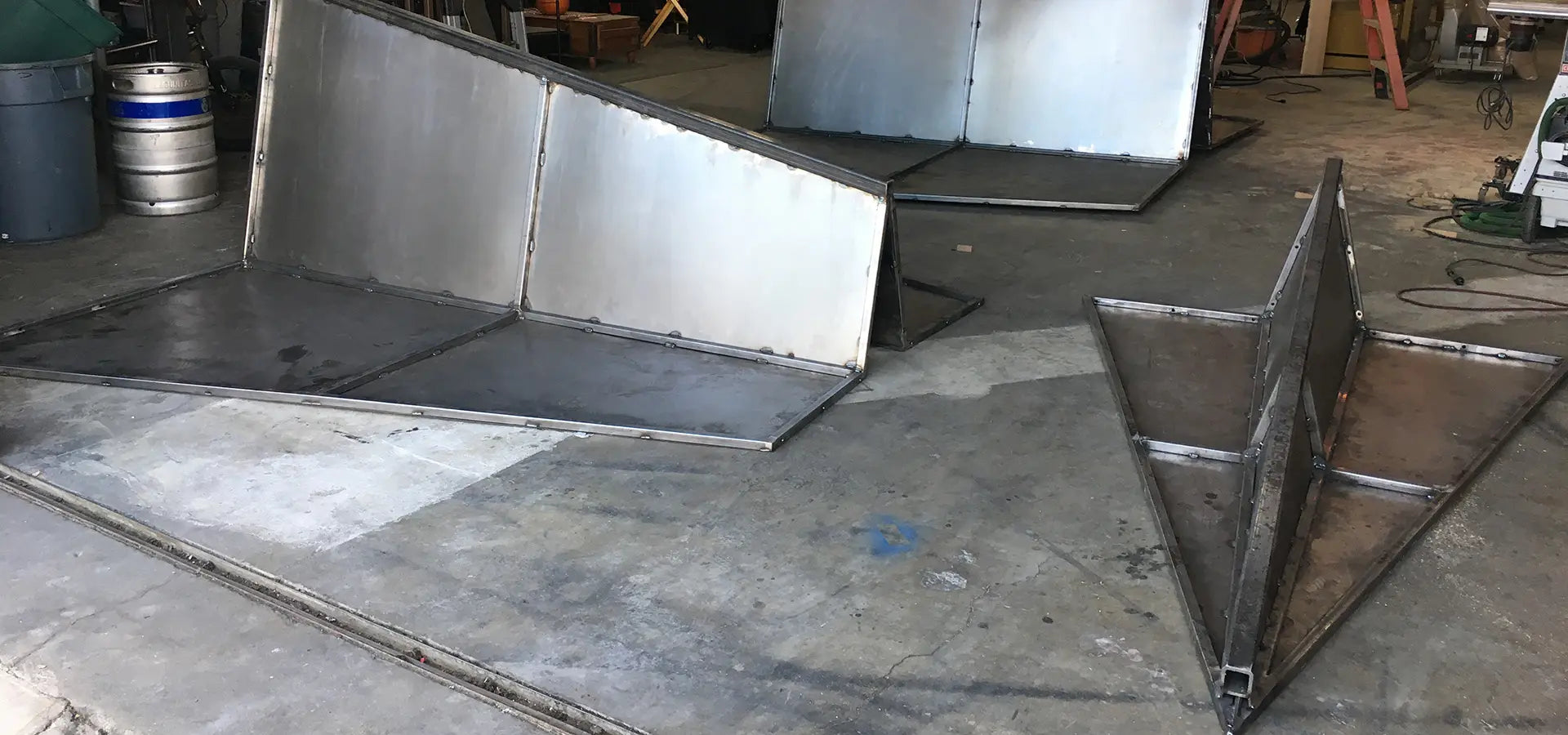 Metalwork in progress on a concrete floor with various tools and materials in the background.