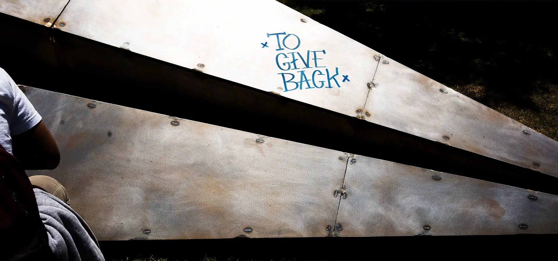 Large Launch Intention metallic paper airplane sculpture close up with the intention "To Give Back" written on the front of the plane.