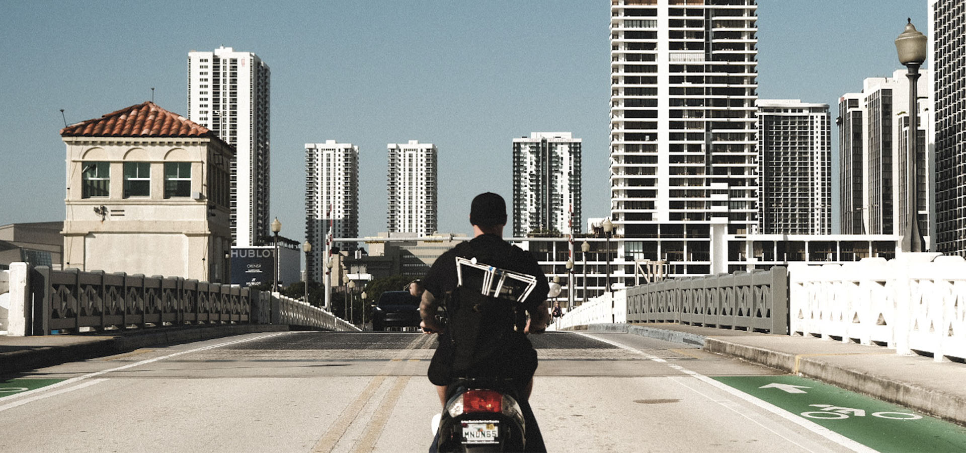 Artist & founder Griffin Loop rides a moped over the causeway to the install of Launch Intention's activation at Context Art Miami during Art Basel.