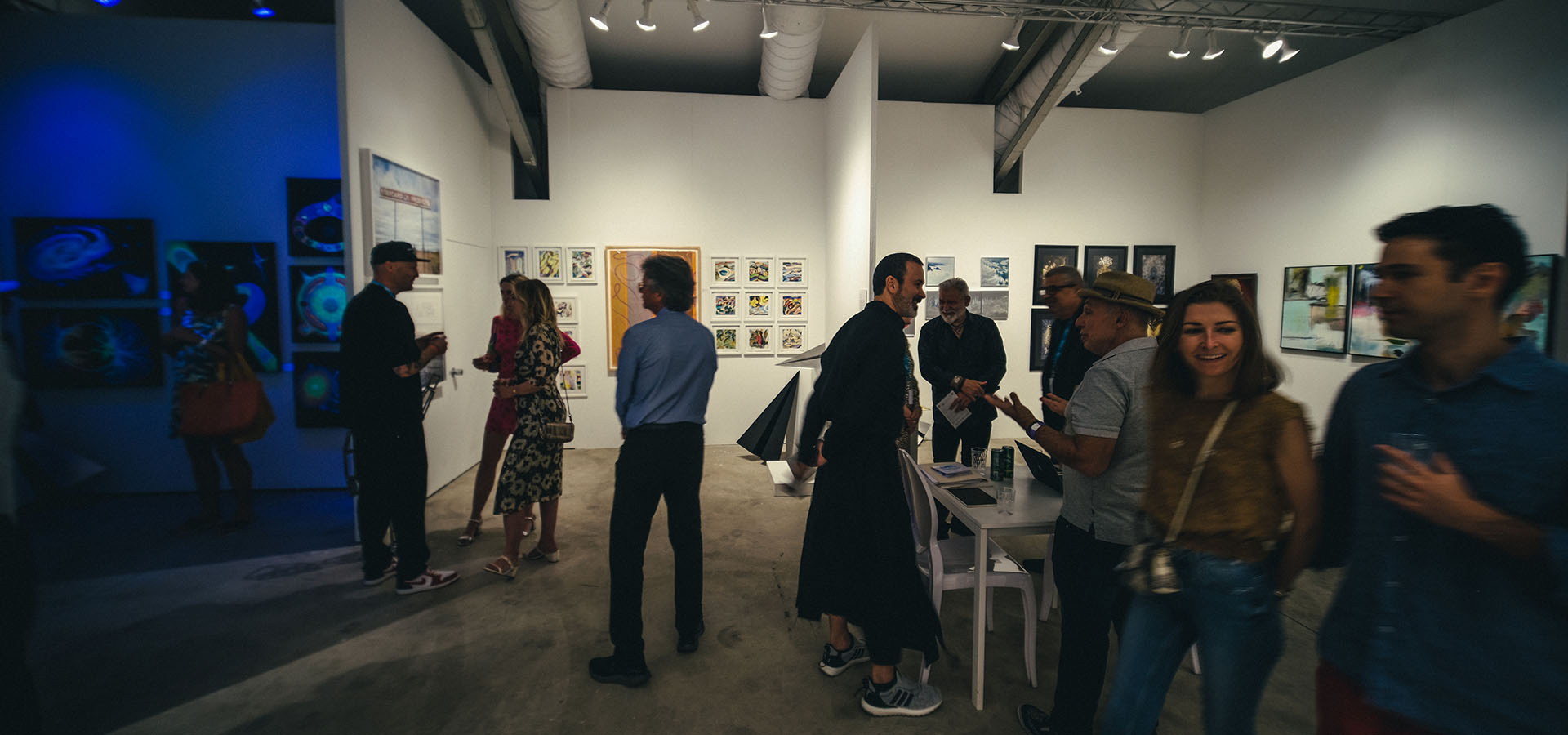 People visiting with artist Griffin Loop at Launch Intention's art gallery at the Context Art Miami tent during Art Basel.