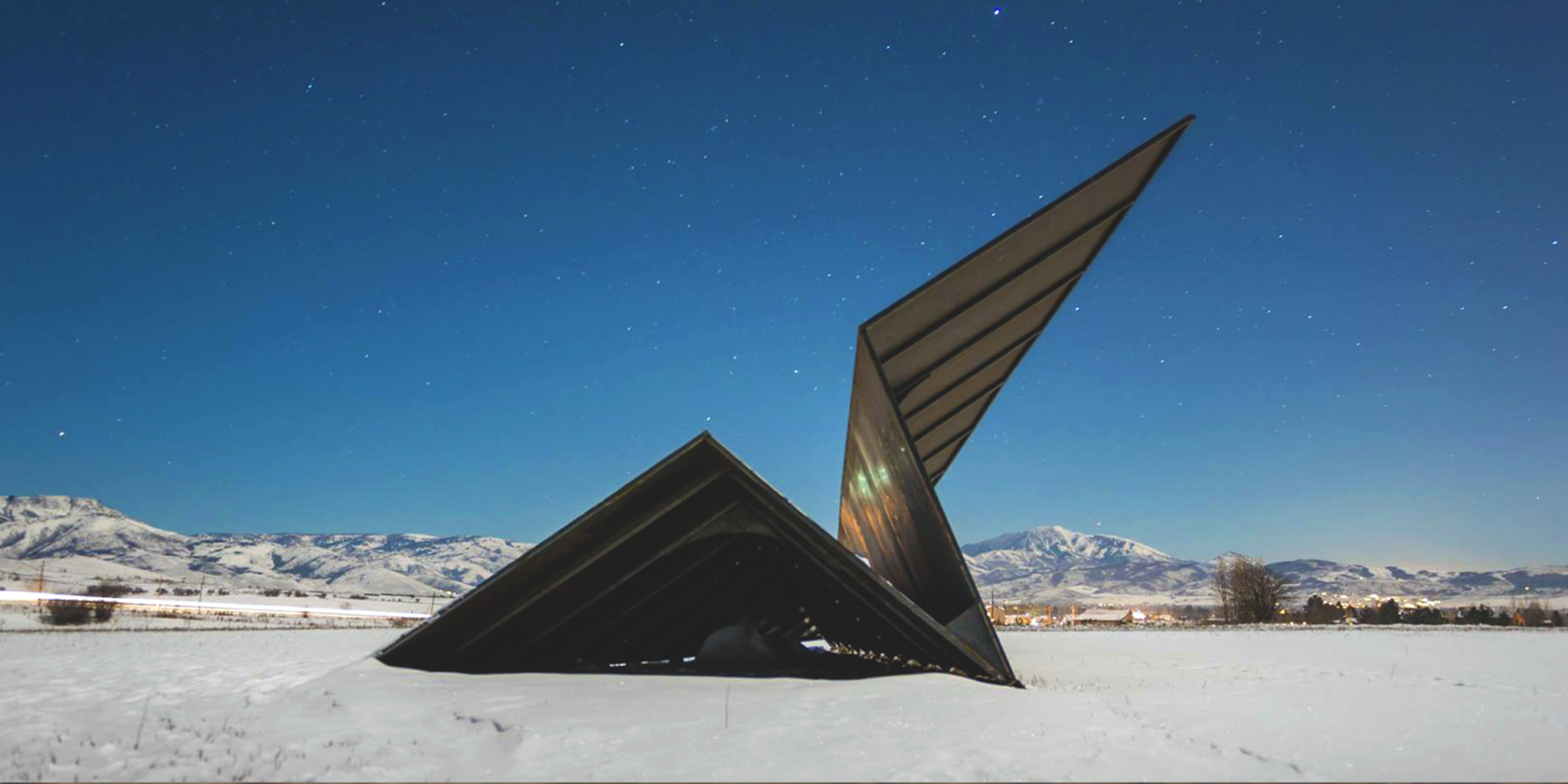 Modern architectural paper airplane sculpture by Launch Intention in a snowy landscape with Utah mountains in the background.