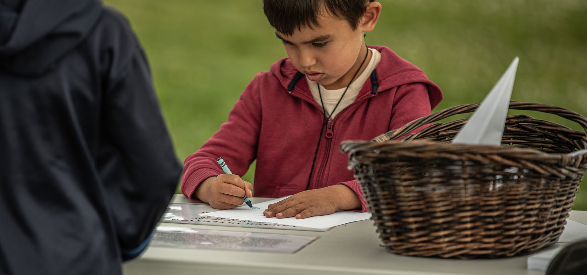 Child writing his intentions on a paper airplane for the Launch Intention activation in San Francisco, CA.